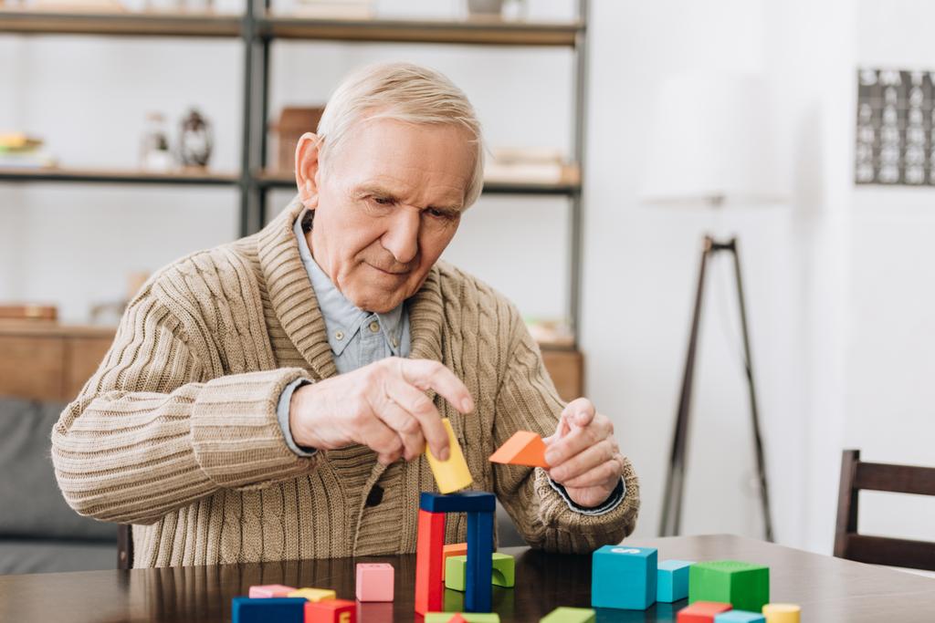 retired man playing with wooden toys at home - Photo, Image