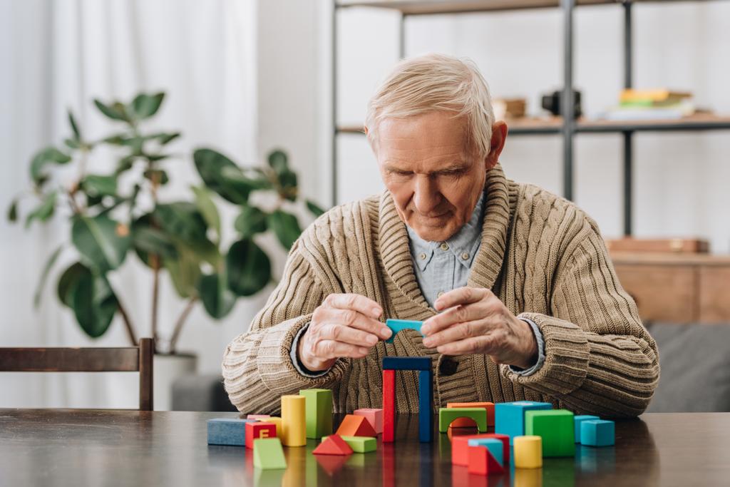 пенсионер играет дома с деревянными игрушками
 - Фото, изображение