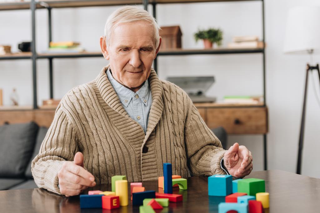 starší muž hraje s dřevěnými hračkami na stole - Fotografie, Obrázek