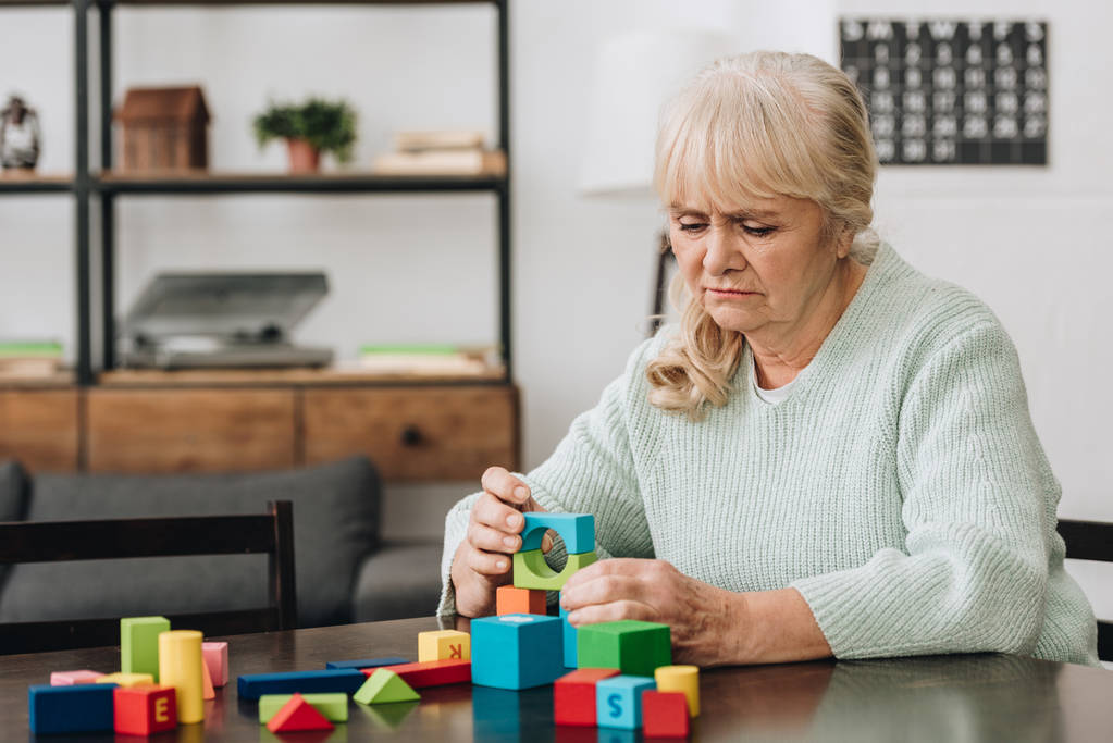 Senior kobieta gra na drewniane zabawki w domu - Zdjęcie, obraz