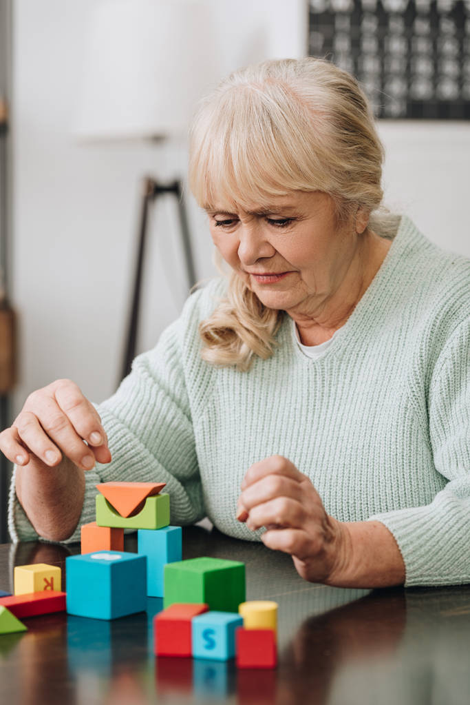 donna anziana bionda che gioca con giocattoli di legno a casa
 - Foto, immagini