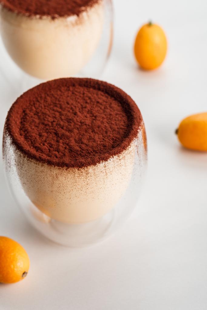 tiramisu desserts with cocoa powder and kumquats in two glasses - Photo, Image