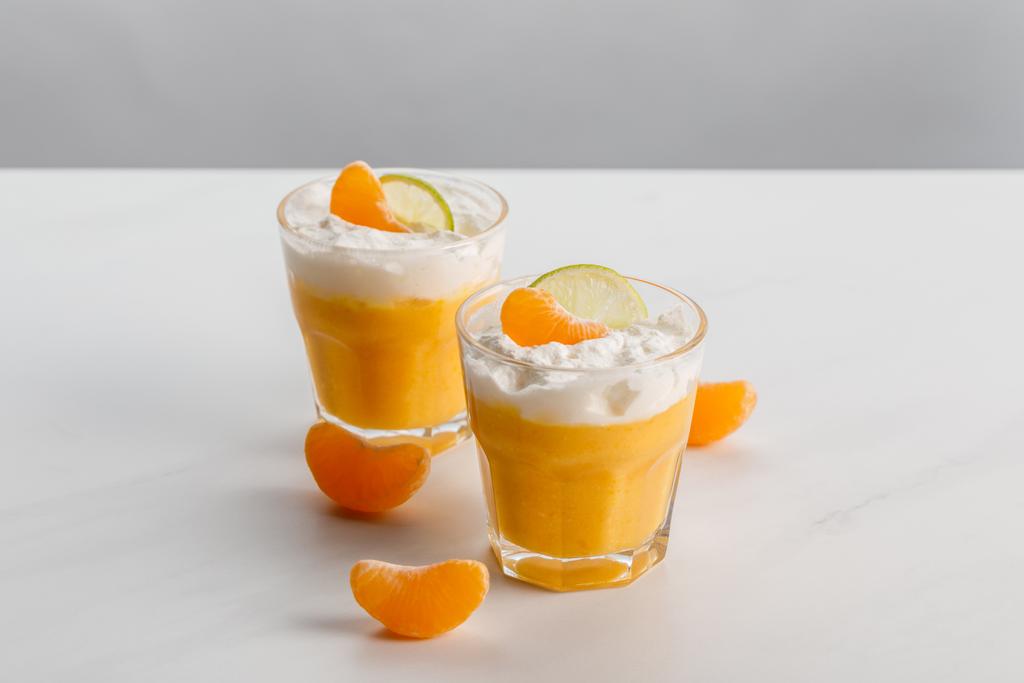 Gläser mit orangefarbenen Desserts mit Mandarine und Limettenscheiben - Foto, Bild