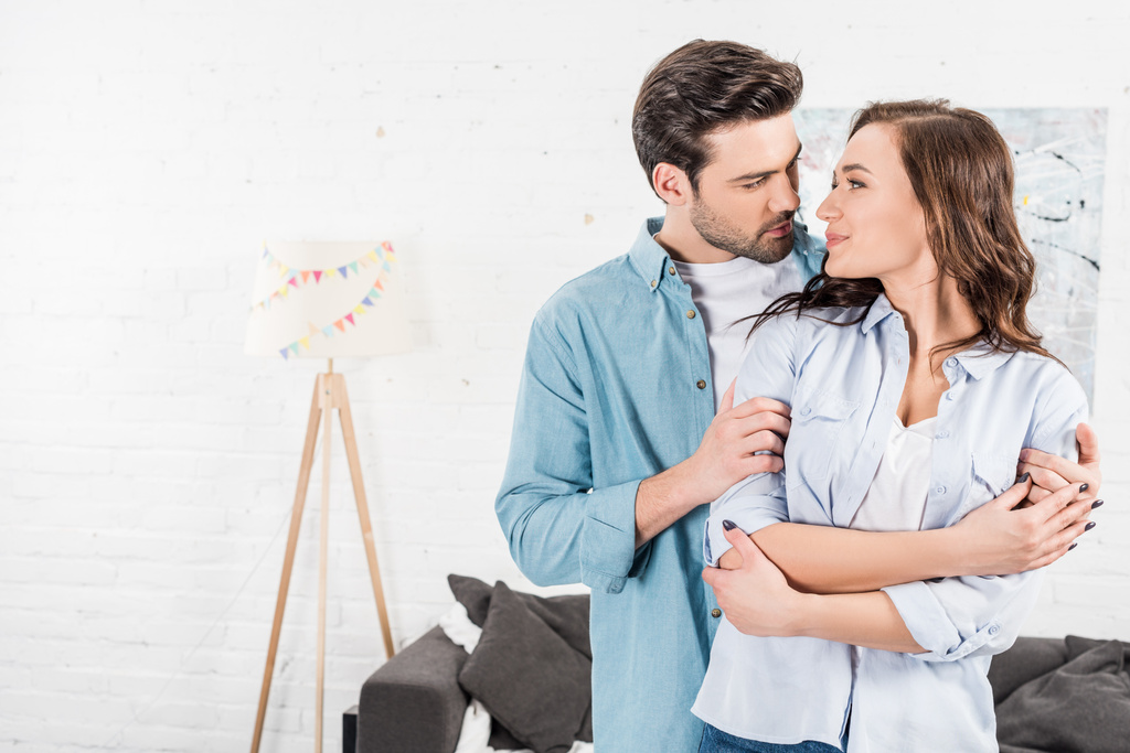 man tenderly embracing attractive woman at home  - Photo, Image