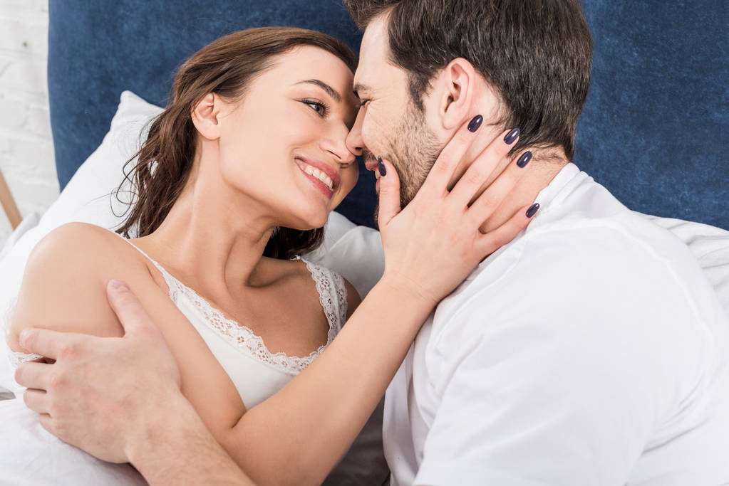 coppia sorridente che si abbraccia e si guarda a letto
 - Foto, immagini