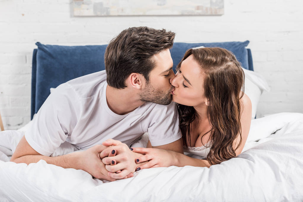 beautiful couple in nightwear kissing in bed at home - Photo, Image
