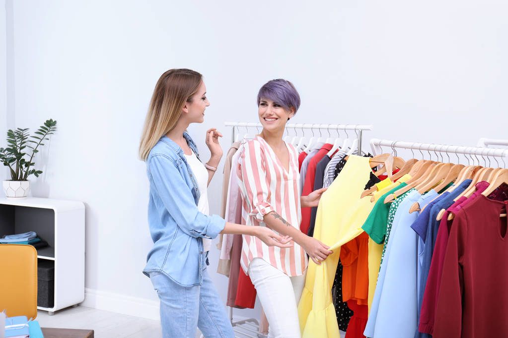 Молодой стилист помогает клиенту выбрать одежду в помещении
 - Фото, изображение