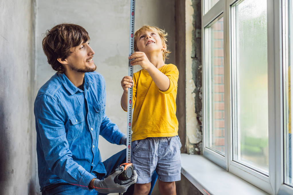 Ragazzino che gioca con lo strumento durante la riparazione della finestra con papà insieme durante la ristrutturazione in casa
. - Foto, immagini