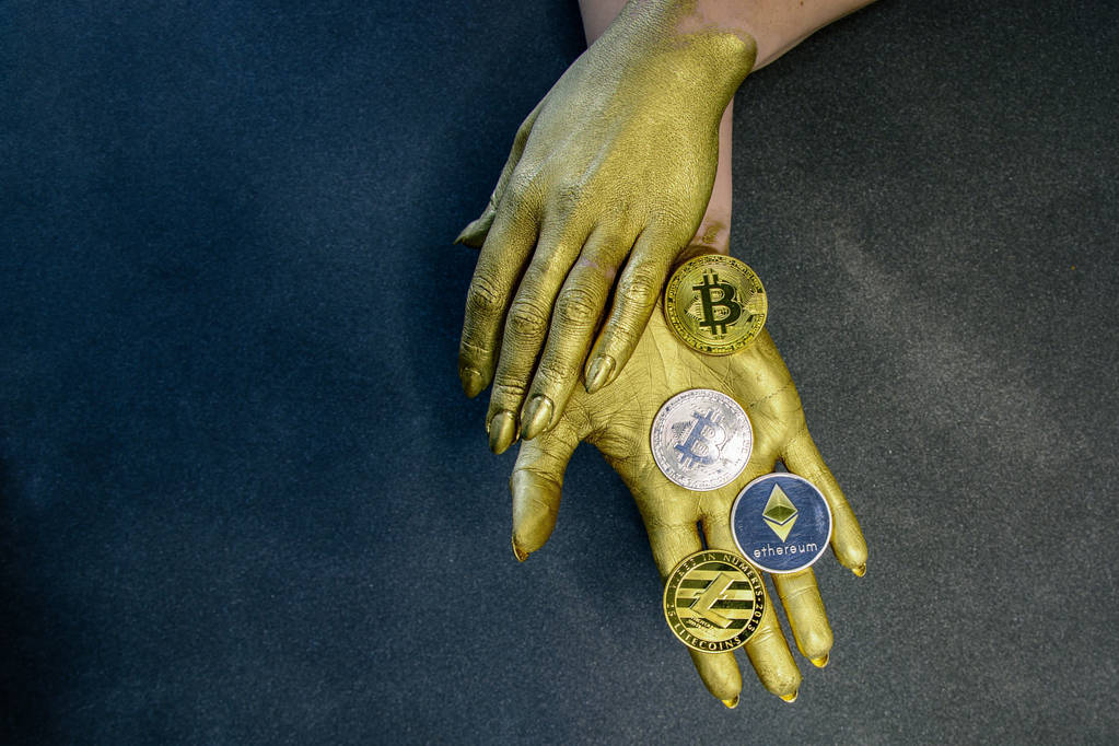 Mit Goldfarbe bemalte Frauenhände halten goldene Bitcoins und Litecoins in der Hand - Foto, Bild