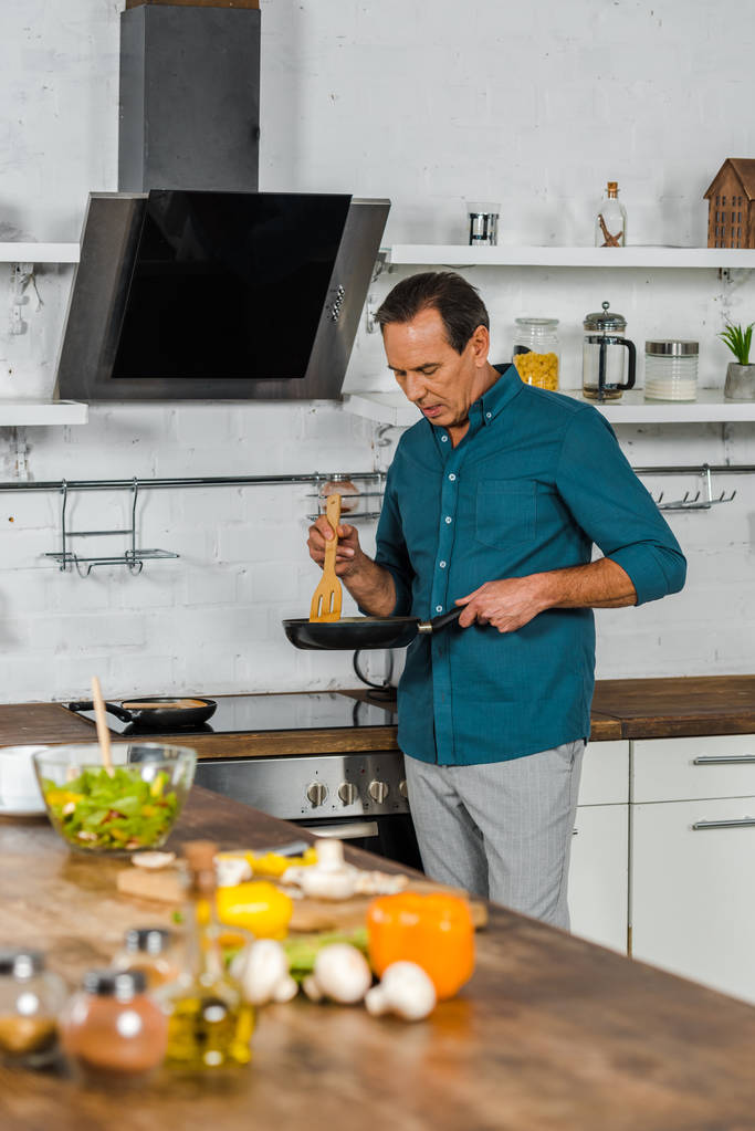 вибірковий фокус красивого зрілого чоловіка, який готує овочі на кухні
 - Фото, зображення