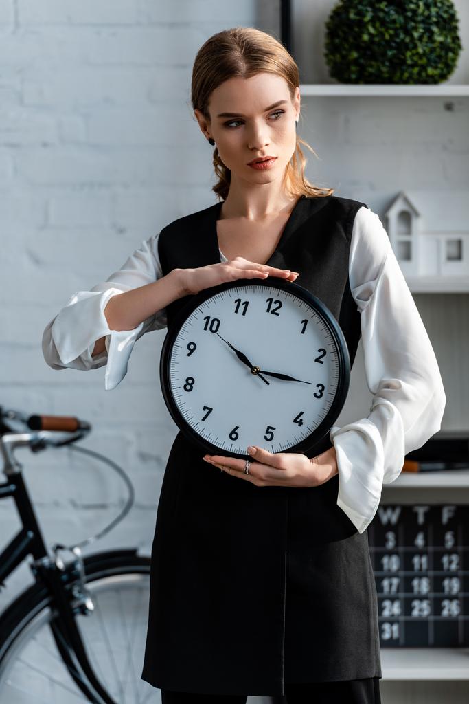 Kobieta w wizytowym gospodarstwa zegar w miejscu pracy - Zdjęcie, obraz