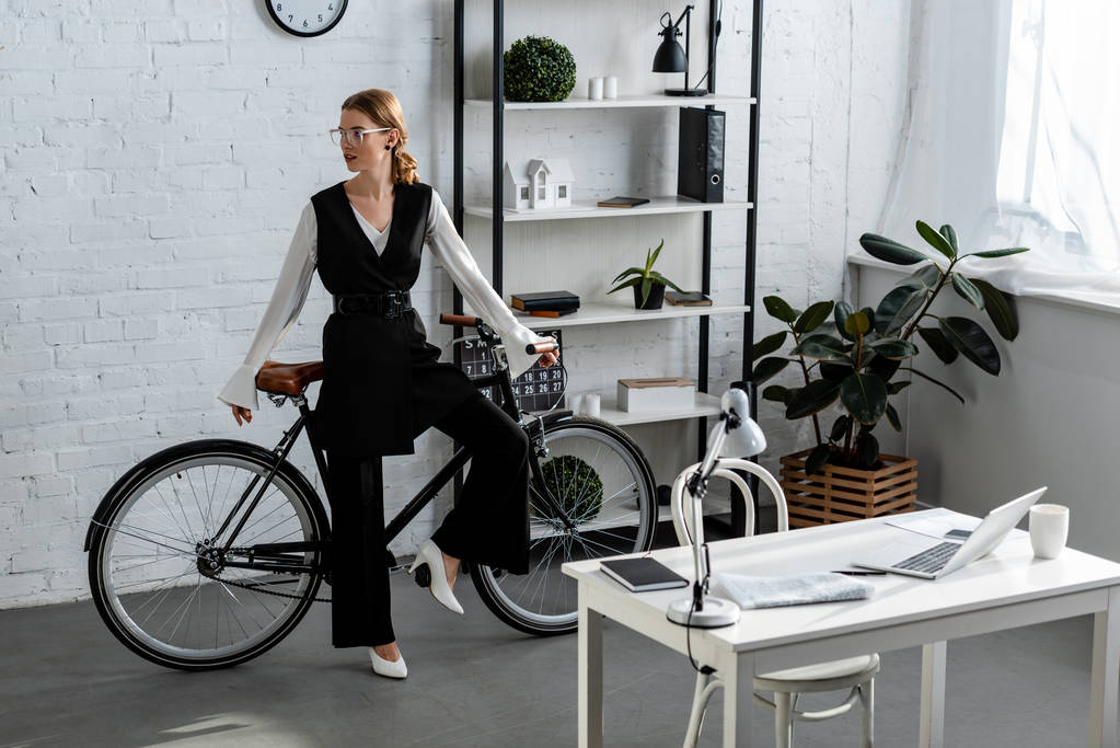 бізнес-леді в офісному одязі з велосипедом в сучасному офісі
  - Фото, зображення