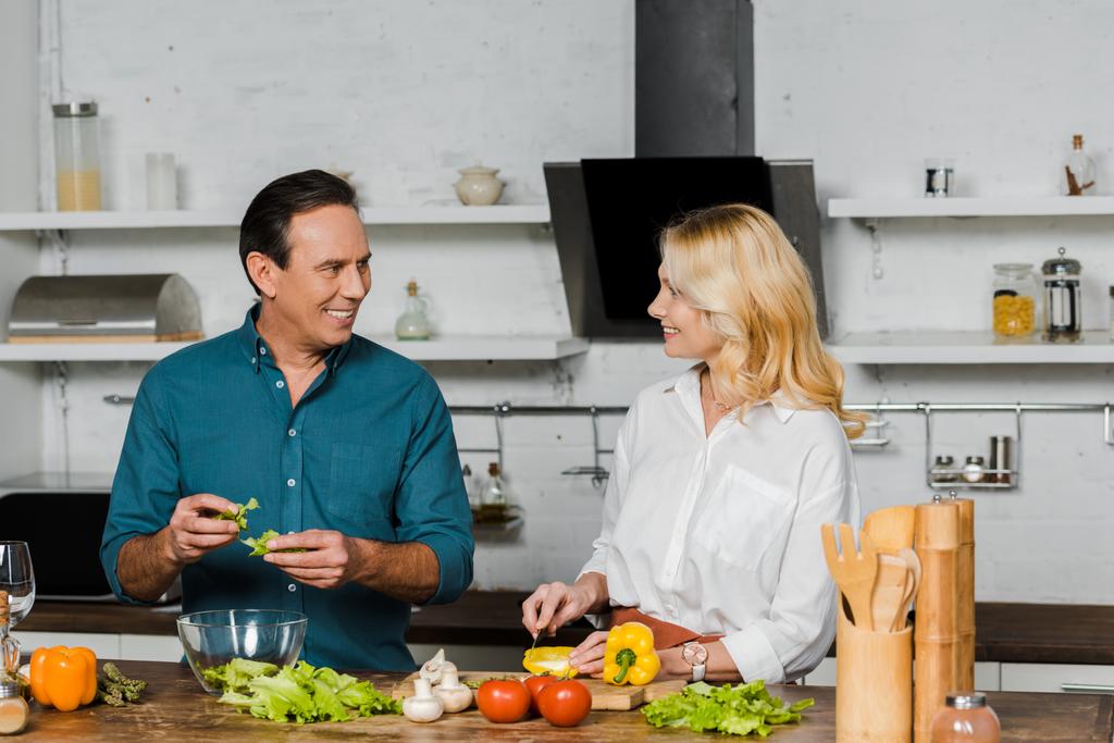 mature femme et mari cuisine salade dans la cuisine et regarder l'autre
 - Photo, image