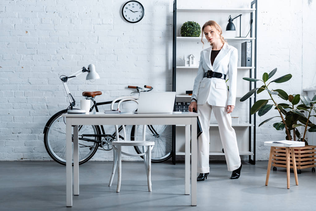 stijlvolle zakenvrouw in formele slijtage kijken camera in moderne kantoor interieur - Foto, afbeelding