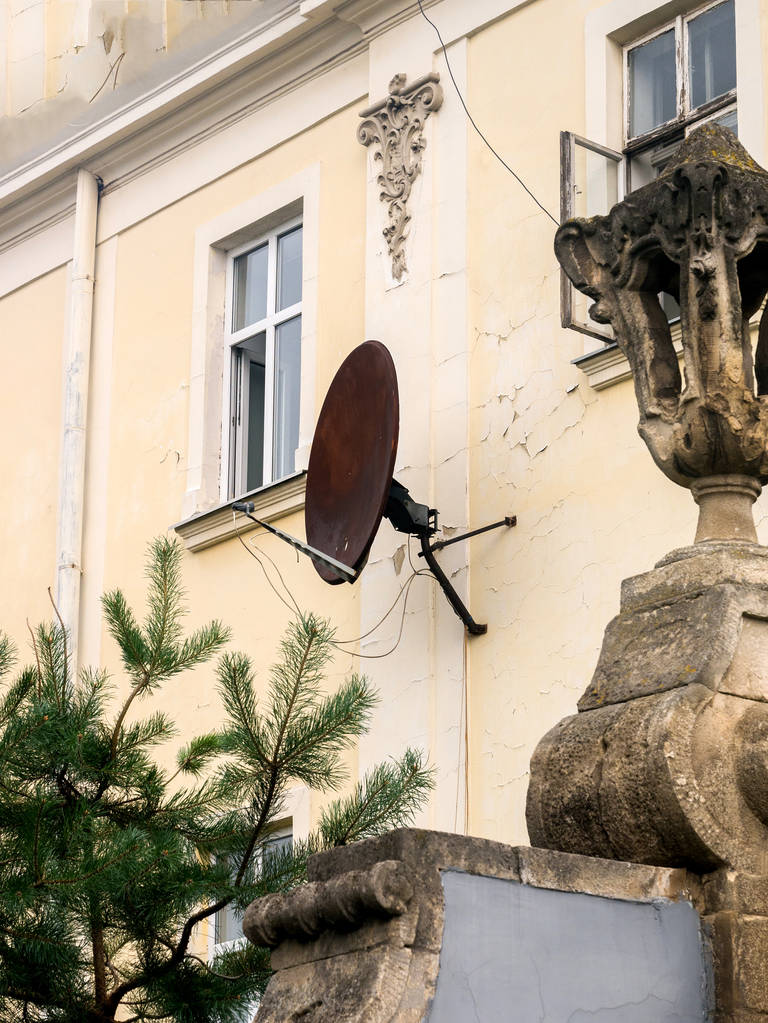 Ржавая спутниковая тарелка на фасаде дома
 - Фото, изображение