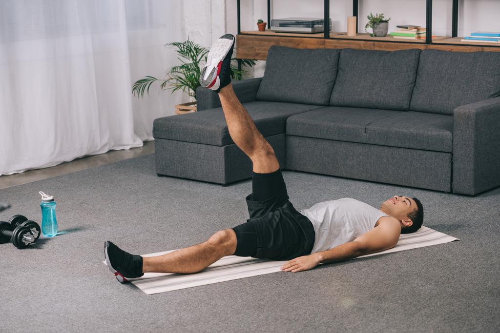 BI rasové sportovec dělá cvičení na nohy vleže na fitness mat - Fotografie, Obrázek