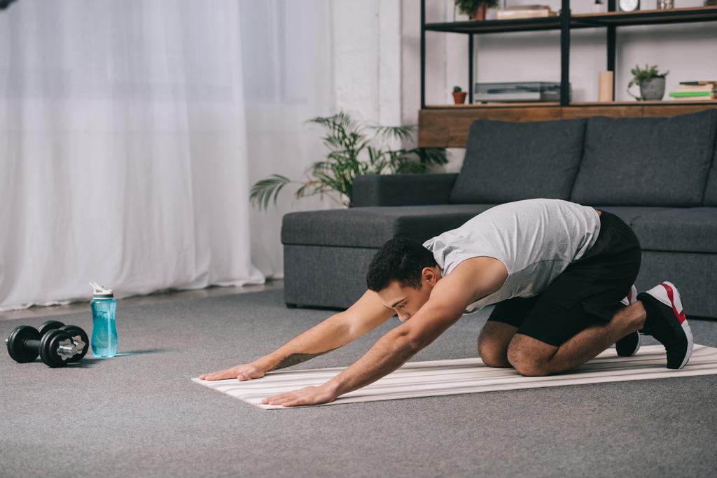 uomo bi-razziale facendo esercizio di stretching per la schiena sul tappeto fitness
 - Foto, immagini