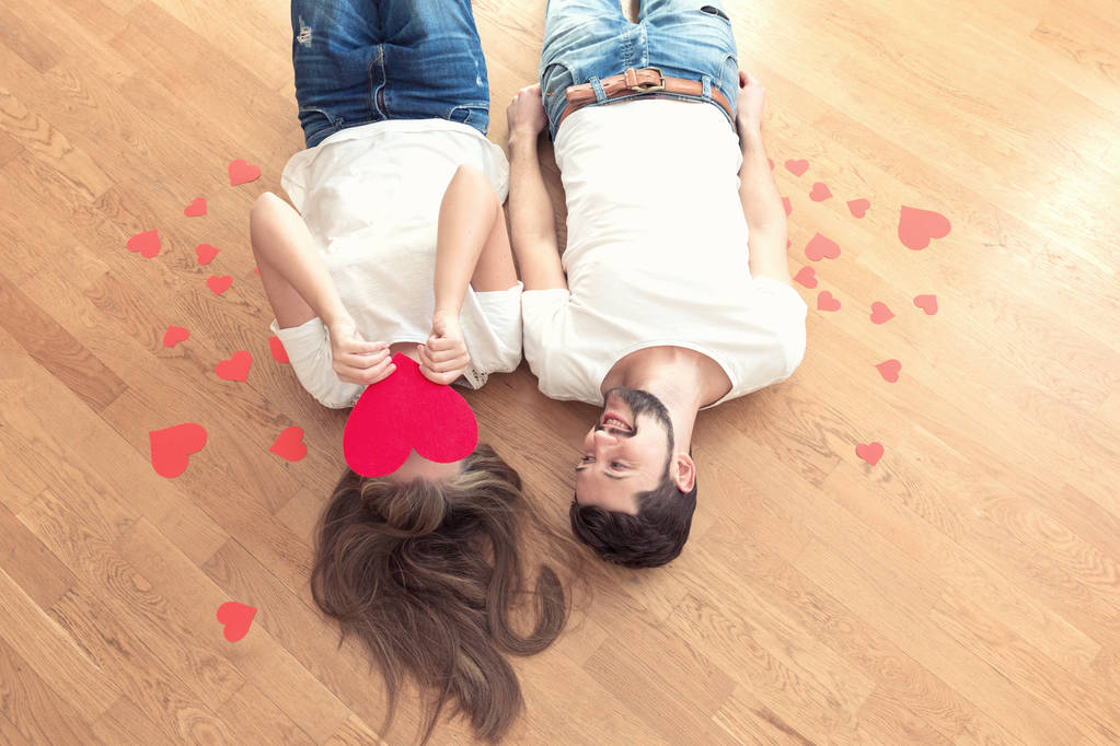 Engraçado namorados casal está deitado no chão. Menina cobrir seu rosto com o coração
. - Foto, Imagem