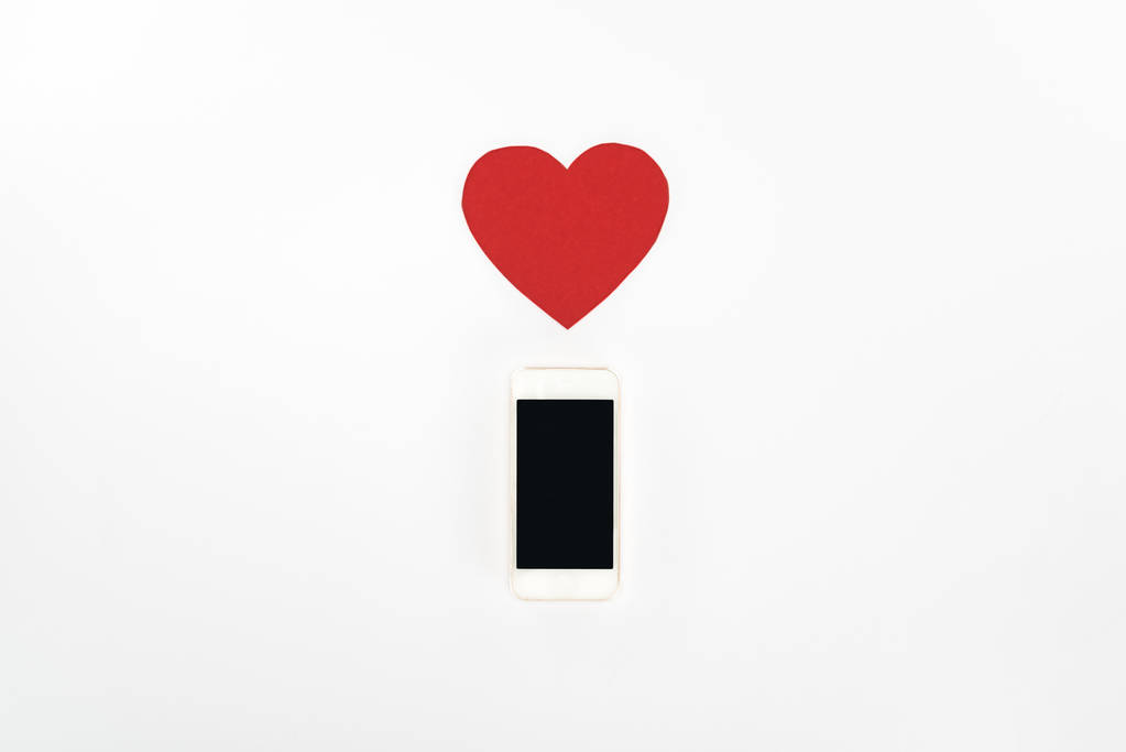 Widok z powyżej czerwony serce symbol i smartphone z pustego ekranu na białym, st Walentynki dzień koncepcji tle - Zdjęcie, obraz