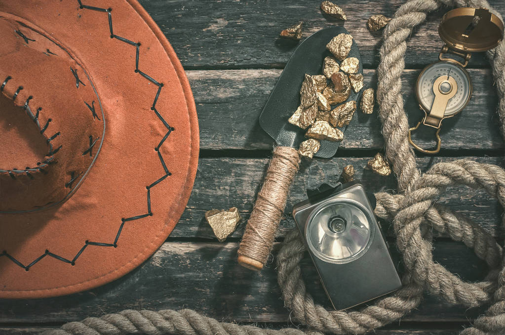 COMPAS, ψήγματα χρυσού, το φτυάρι, σχοινί και vintage φακό στο φόντο παλαιωμένο ξύλινο τραπέζι. Θησαυρός κυνηγό ή goldminer έννοια. - Φωτογραφία, εικόνα