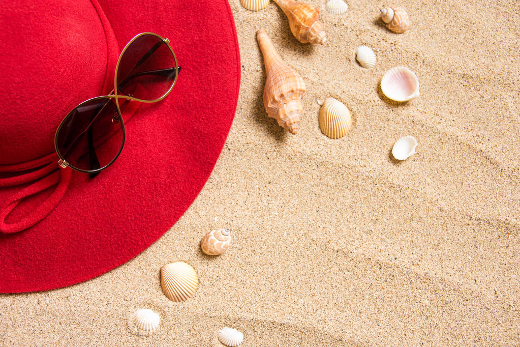 chapéu vermelho na praia de areia com óculos de sol, conchas e espaço de cópia para texto
. - Foto, Imagem