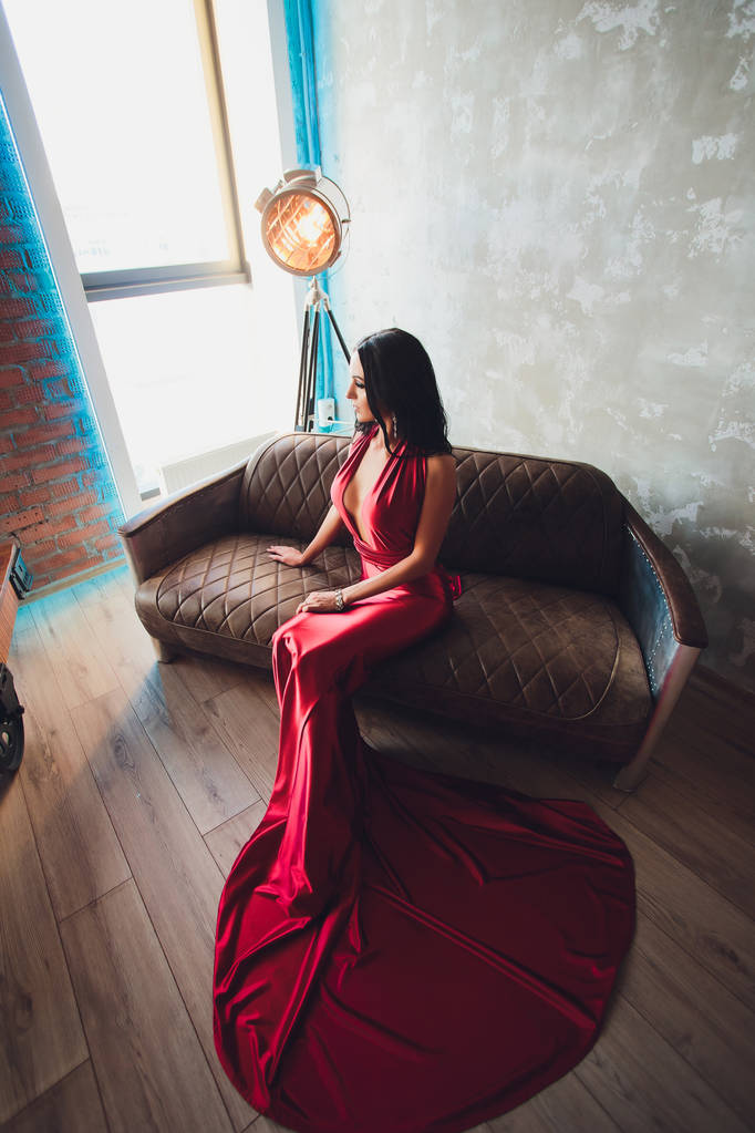 mode studio foto van prachtige vrouw met donker haar en avond make-up, de luxe rode jurk draagt. turquoise neon lichten film spotlight - Foto, afbeelding