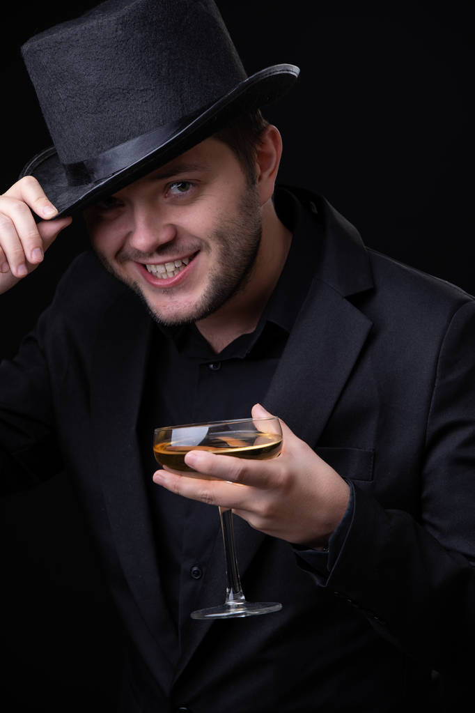 Mutlu bir şarap kadehi ile siyah şapkalı adam fotoğrafı - Fotoğraf, Görsel
