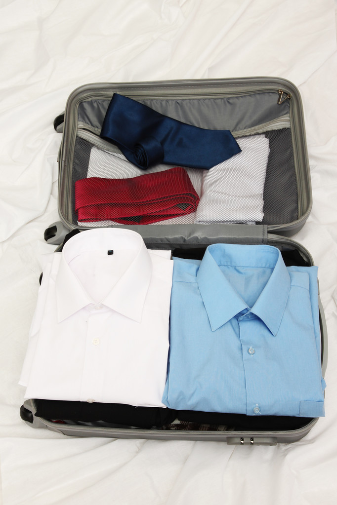 Open grey suitcase with clothing on bed - Photo, Image