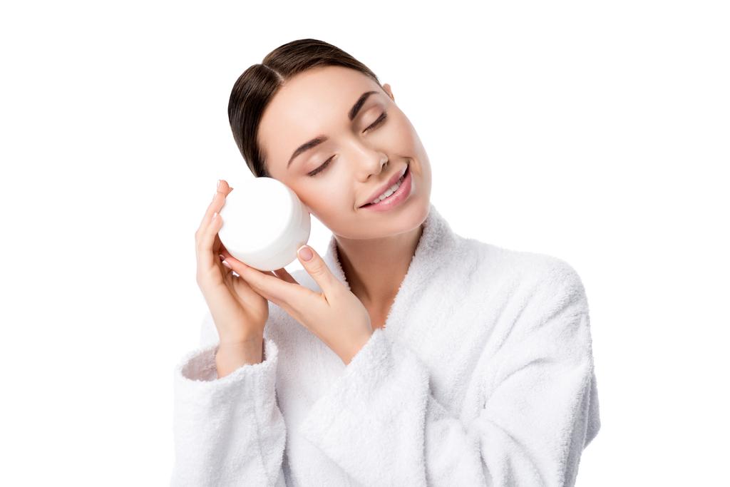 femme en peignoir avec les yeux fermés tenant crème visage isolé sur blanc
 - Photo, image
