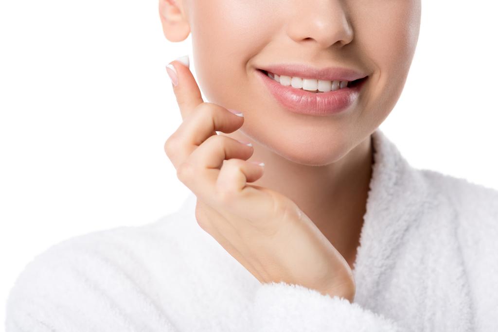 vista cortada de mulher sorridente em roupão de banho com creme facial na mão isolado no branco
 - Foto, Imagem