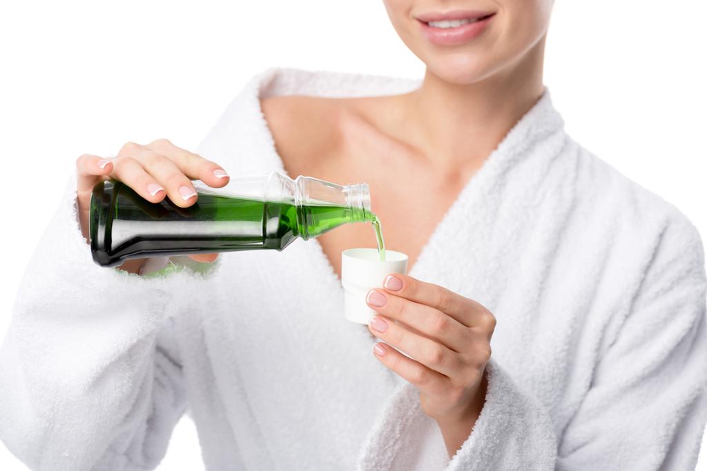 rajattu näkymä hymyilevä nainen kylpytakki kaatamalla suuvettä cup eristetty valkoinen
 - Valokuva, kuva