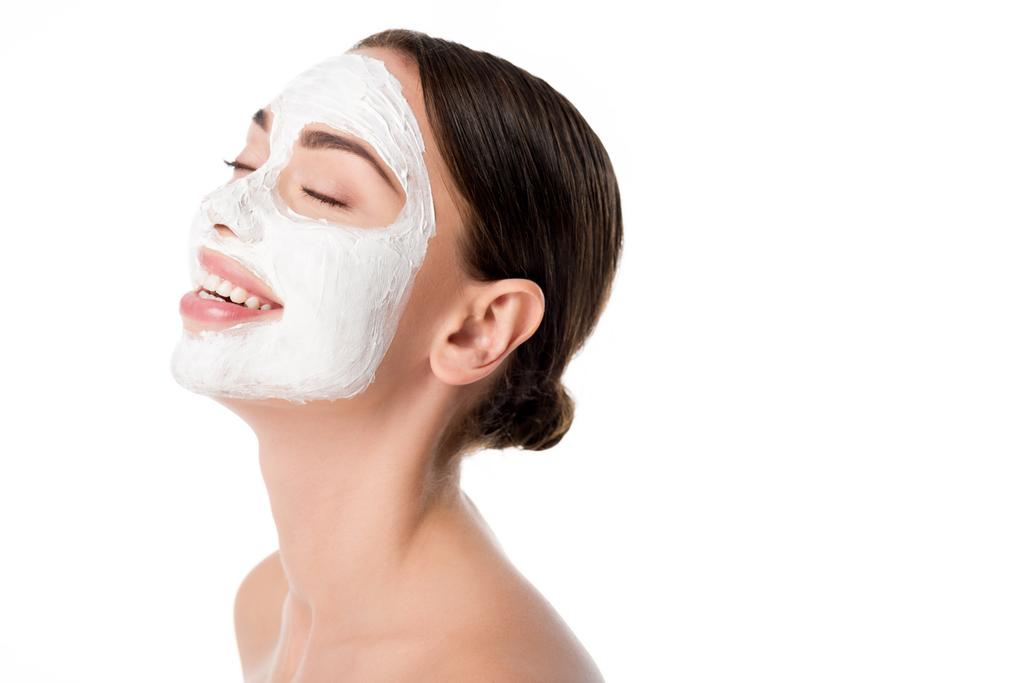 mujer sonriente con mascarilla facial para el cuidado de la piel y ojos cerrados aislados en blanco
 - Foto, imagen