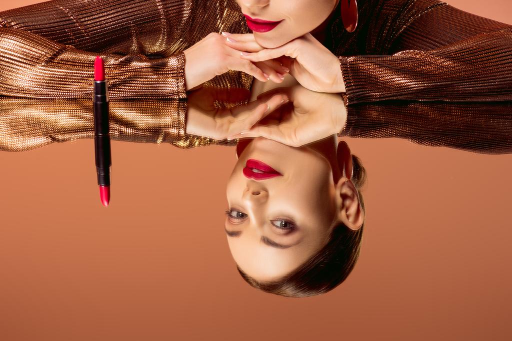 gedeeltelijke weergave van mooie vrouw met glamoureuze make-up, rode lippenstift en spiegel reflectie geïsoleerd op oranje - Foto, afbeelding