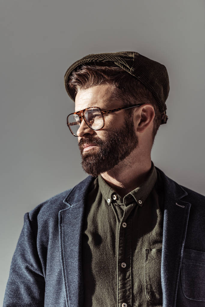 крупним планом вигляд красивого бородатого чоловіка в окулярах і кепка ізольовані на сірому
 - Фото, зображення