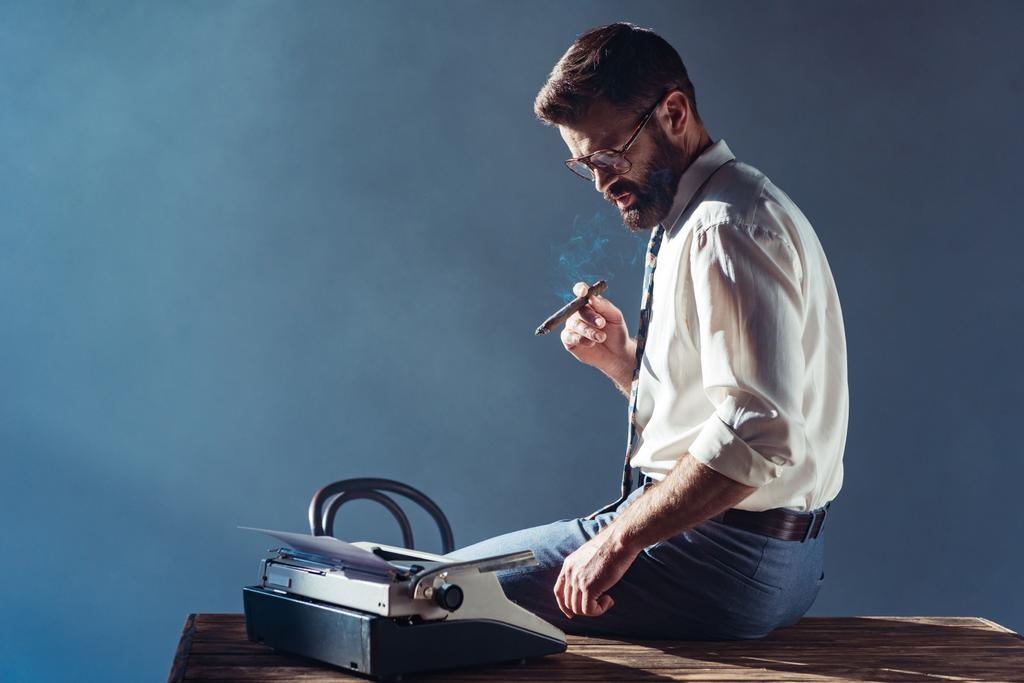 bonito homem fumar e olhando para máquina de escrever
 - Foto, Imagem