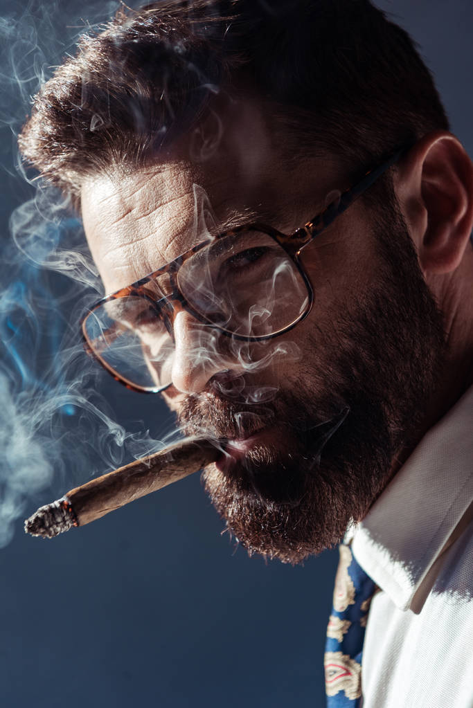 guapo barbudo hombre en gafas de fumar y mirando a la cámara
 - Foto, Imagen