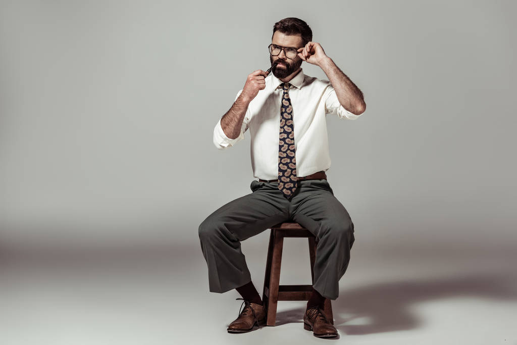 guapo barbudo hombre en gafas sentado en silla y fumar pipa
 - Foto, imagen
