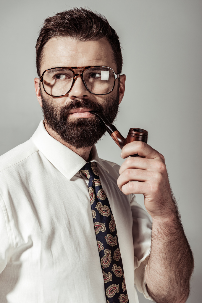 красивий бородатий чоловік в окулярах, сорочці і краватці курильної труби ізольовані на сірому
 - Фото, зображення