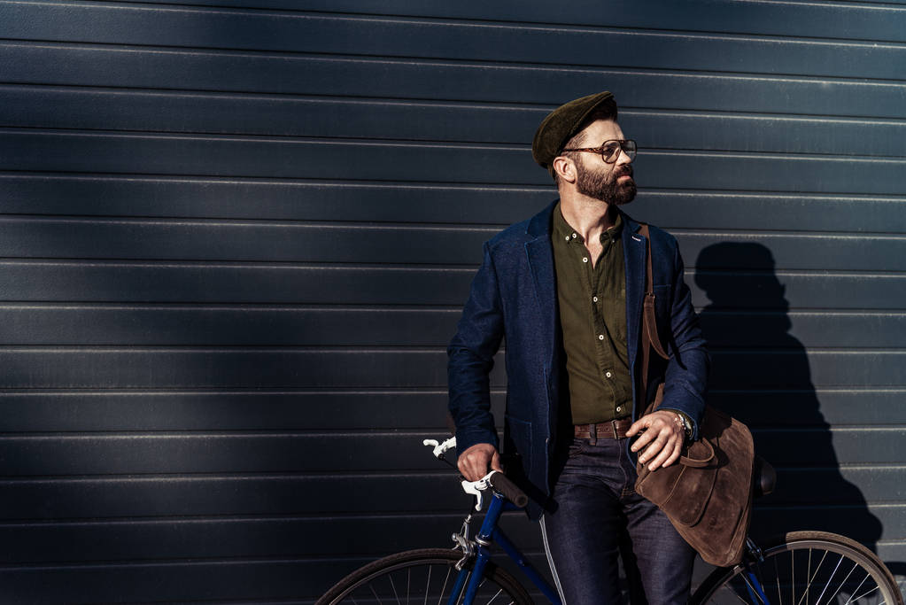 bel homme barbu dans des lunettes et casquette tenant vélo
 - Photo, image