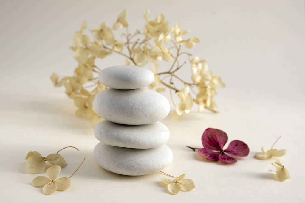 Harmonie et équilibre, cairns, pierres d'équilibre simples sur fond blanc, sculpture rock zen, cinq cailloux blancs, tour unique, simplicité, hortensia sèche fleur blanche et rouge
 - Photo, image