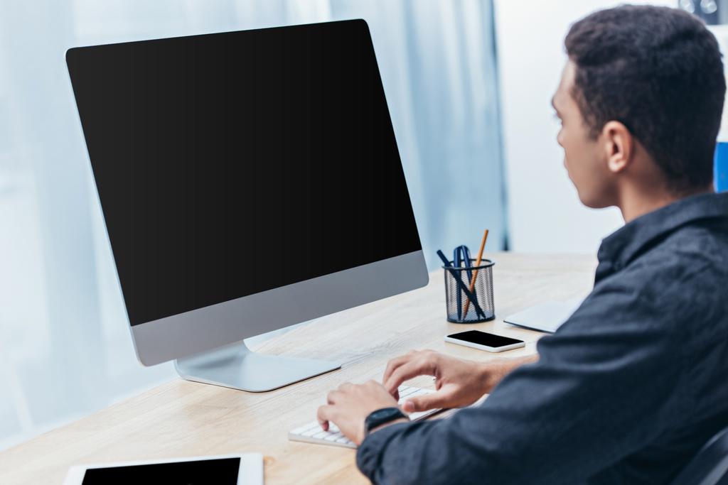 νεαρός επιχειρηματίας χρησιμοποιώντας υπολογιστή με κενή οθόνη στο γραφείο - Φωτογραφία, εικόνα
