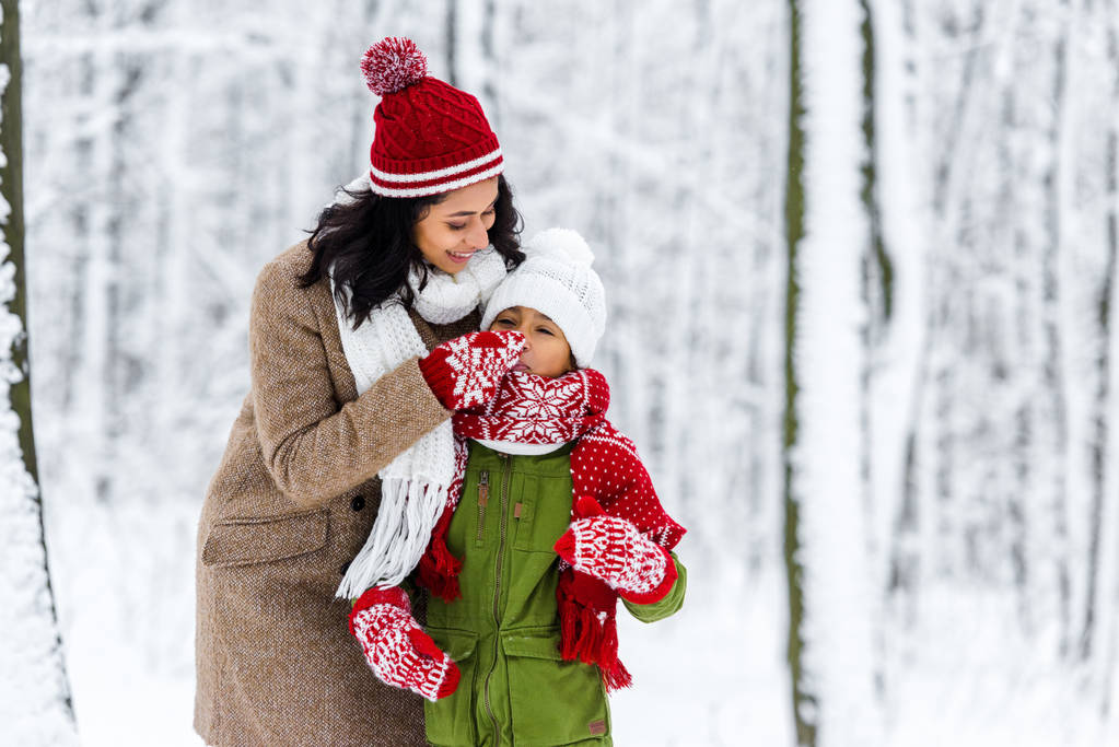 cheerful african american mom touching nose of cute daughter in winter park - Photo, Image