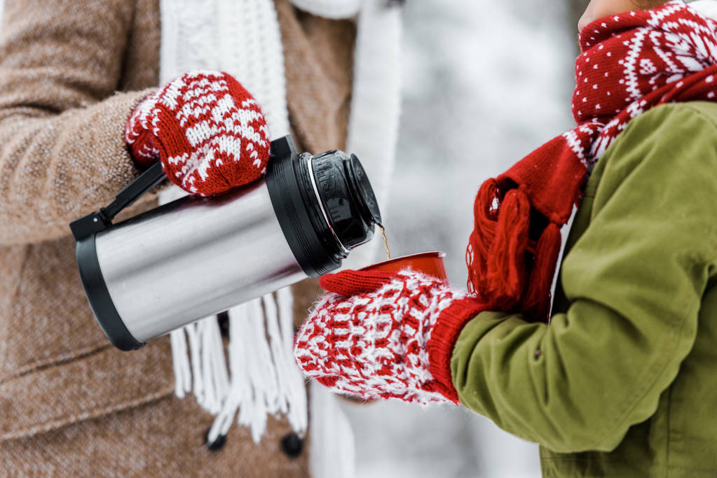 女性が冬子を持って赤カップにポットからお茶を注ぐのビューをトリミング - 写真・画像