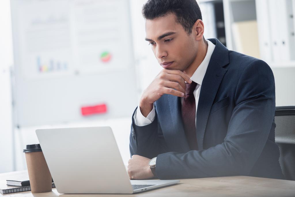 giovane uomo d'affari concentrato in giacca e cravatta che lavora con il computer portatile in ufficio
 - Foto, immagini