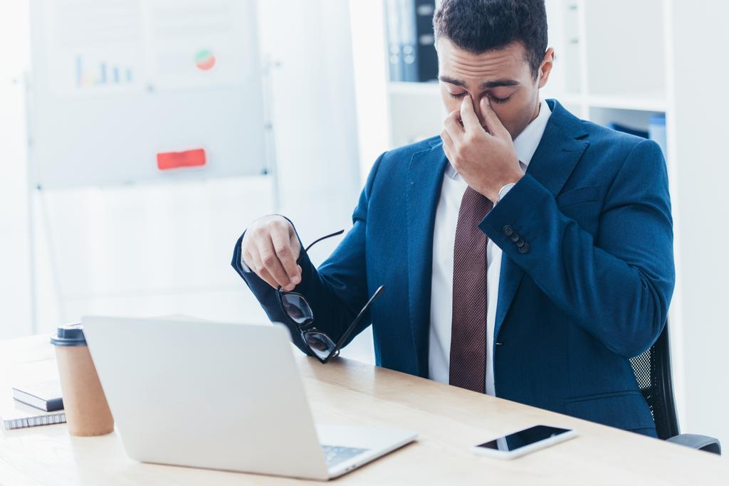 cansado jovem empresário segurando óculos e esfregando nariz ponte no local de trabalho
 - Foto, Imagem
