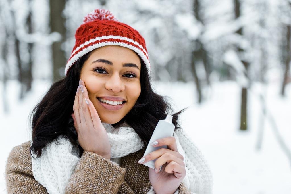 attractive african american woman touching cheek in winter forest - Photo, Image