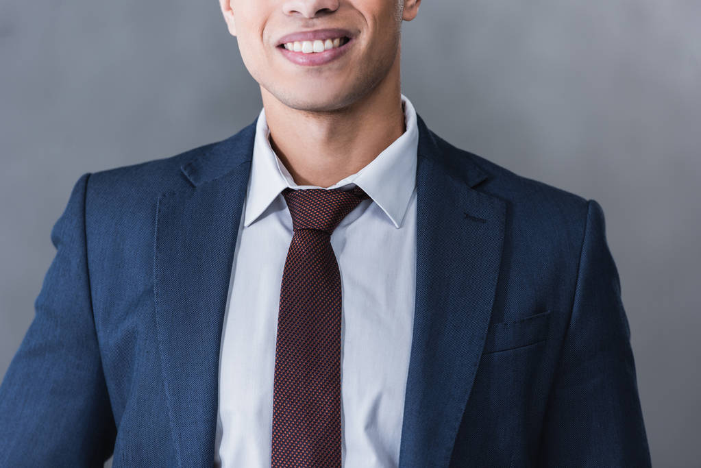cropped shot of smiling young businessman in formal wear on grey - Photo, Image