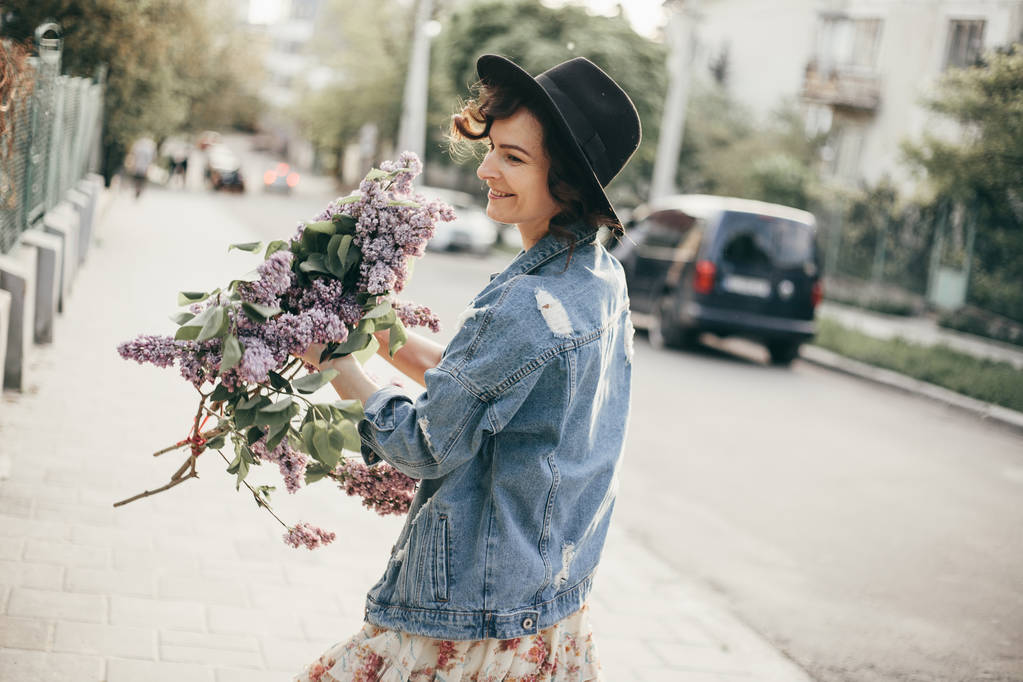 ライラックの花を持つ美しい若い女性の屋外のファッション写真 - 写真・画像