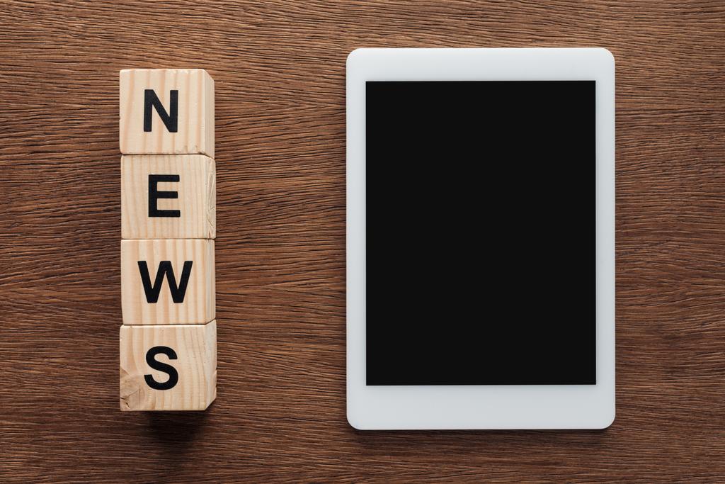 верхний вид планшета с чистым экраном и деревянными кубиками со словом новости на деревянном столе
 - Фото, изображение