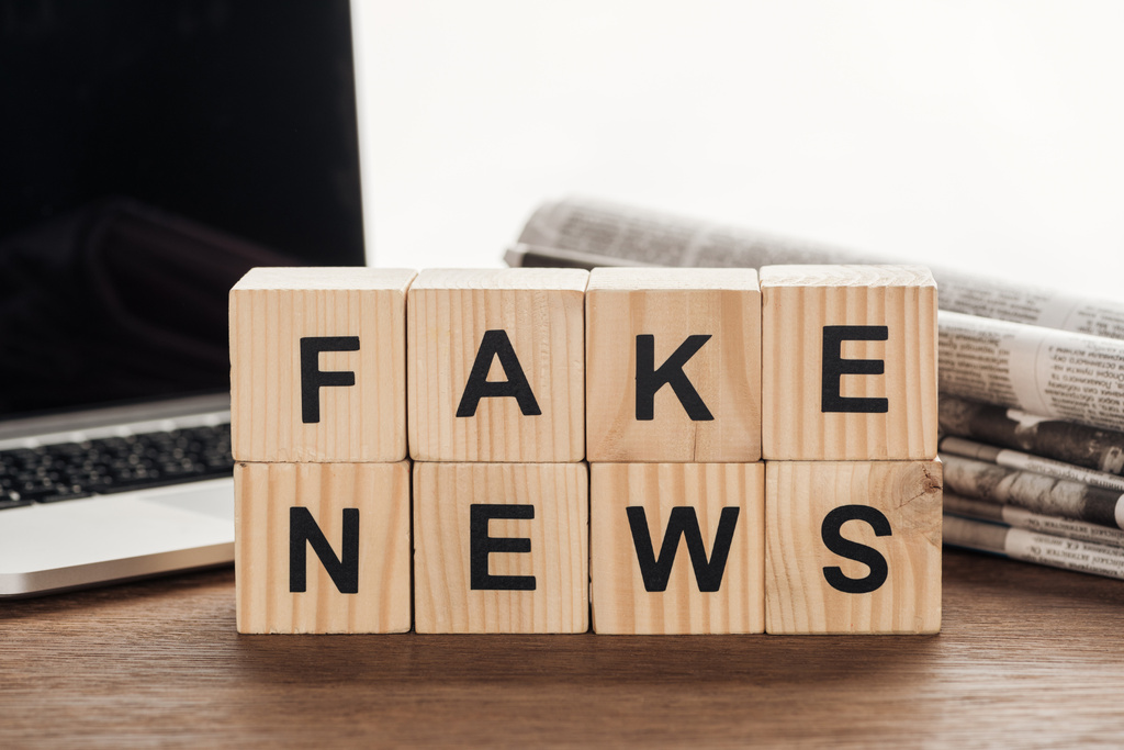 Holzwürfel mit Wörtern Fake News, Laptop und Zeitungen auf Holztischplatte - Foto, Bild